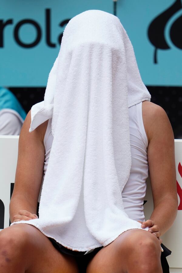 Iga Swiatek of Poland covers her face with a towel during her match against United States' Madison Keys at the Madrid Open tennis tournament in Madrid, Spain, Wednesday, April 30, 2025. (AP Photo/Manu Fernandez)