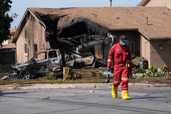 Authorities work the scene where a small plane crashed into a San Diego neighborhood, setting several homes on fire and forcing evacuations along several blocks early Thursday, May 22, 2025. (AP Photo/Gregory Bull)