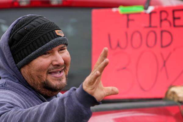 William Amaya waves to a customer while selling firewood Monday, Jan. 20, 2025, in Houston, ahead of a winter storm predicted to dump several inches of snow in Southeast Texas. (AP Photo/David J. Phillip)