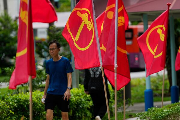 A man walks next to workers' party flags at Hougang area in Singapore, Friday, May 2, 2025. (AP Photo/Vincent Thian)