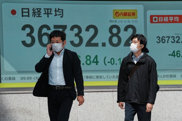 People walk in front of an electronic stock board showing Japan's Nikkei index at a securities firm Thursday, May 8, 2025, in Tokyo. (AP Photo/Eugene Hoshiko)