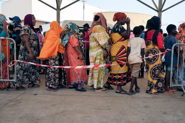 Women wait in line at a water distribution point in Mamoudzou, Mayotte, Saturday, Dec. 21, 2024. (AP Photo/Adrienne Surprenant)