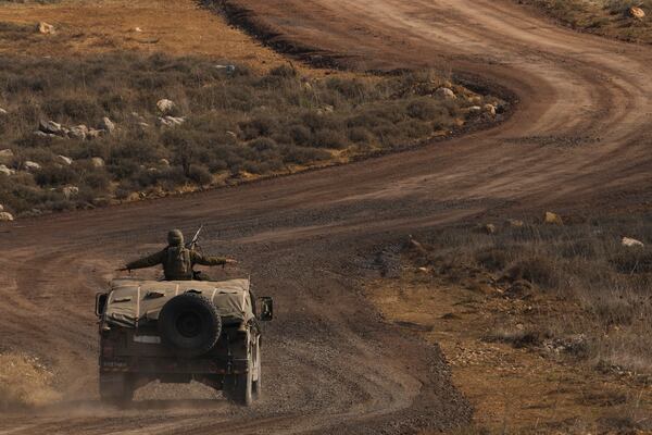 An Israeli soldier stands on an armoured vehicle on the buffer zone after crossing the security fence near the so-called Alpha Line that separates the Israeli-controlled Golan Heights from Syria, viewed from the town of Majdal Shams, Saturday, Dec. 21, 2024. (AP Photo/Matias Delacroix)