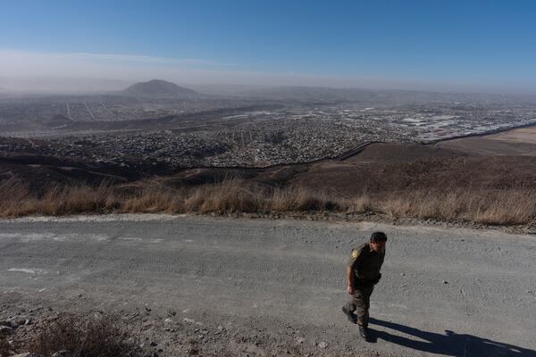 Border Patrol Agent Gutierrez walks along a road near where two border walls separate Mexico from the United States, Thursday, Jan. 23, 2025, in San Diego. (AP Photo/Gregory Bull)