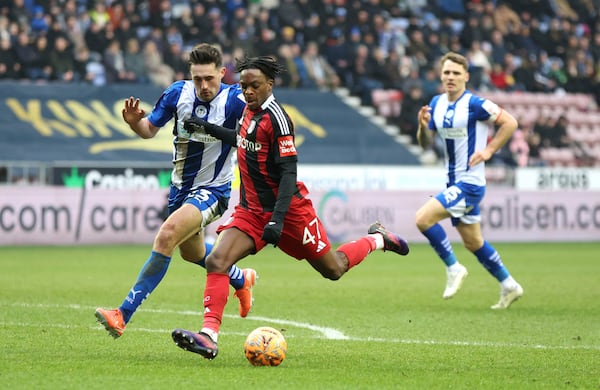 Wigan Athletic's James Carragher, left, and Fulham's Becket Godo battle for the ball during the English FA Cup fourth round soccer match between Wigan Athletic and Fulham at The Brick Community Stadium, Wigan, England, Saturday Feb. 8, 2025. (Barrington Coombs/PA via AP)