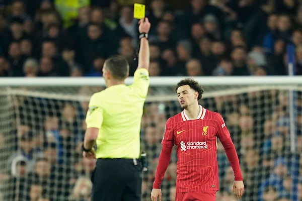 Referee Michael Oliver shows a yellow card to Liverpool's Curtis Jones, right, during the English Premier League soccer match between Everton and Liverpool, Liverpool, England, Wednesday, Feb.12, 2025. (AP Photo/Dave Thompson)