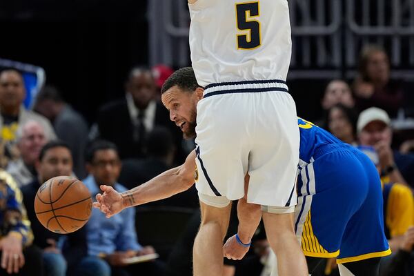 Golden State Warriors guard Stephen Curry, right, passes while defended by Denver Nuggets forward Hunter Tyson (5) during the second half of an NBA basketball game Monday, March 17, 2025, in San Francisco. (AP Photo/Godofredo A. Vásquez)