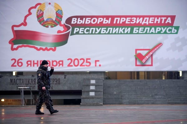 A police officer walks past an election billboard ahead of presidential elections in Minsk, Belarus, Friday, Jan. 24, 2025. (AP Photo/Pavel Bednyakov)