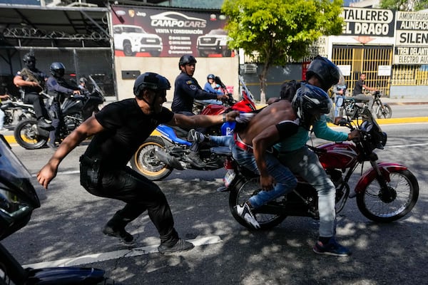 Police pursue opponents of Venezuelan President Nicolas Maduro, two people on the motorcycle at right, during a protest the day before Maduro's inauguration for a third term in Caracas, Venezuela, Thursday, Jan. 9, 2025. (AP Photo/Matias Delacroix)