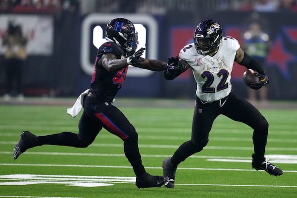 Baltimore Ravens running back Derrick Henry (22) tries to break a tackle by Houston Texans linebacker Christian Harris, left, during the second half of an NFL football game, Wednesday, Dec. 25, 2024, in Houston. (AP Photo/David J. Phillip)