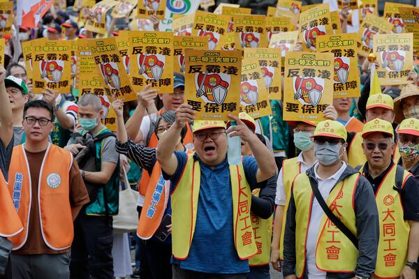 Taiwanese workers hold slogans reading "Anti-bullying Needs to Be Guaranteed.'' during a May Day rally in Taipei, Taiwan, Thursday, May 1, 2025. (AP Photo/Chiang Ying-ying)