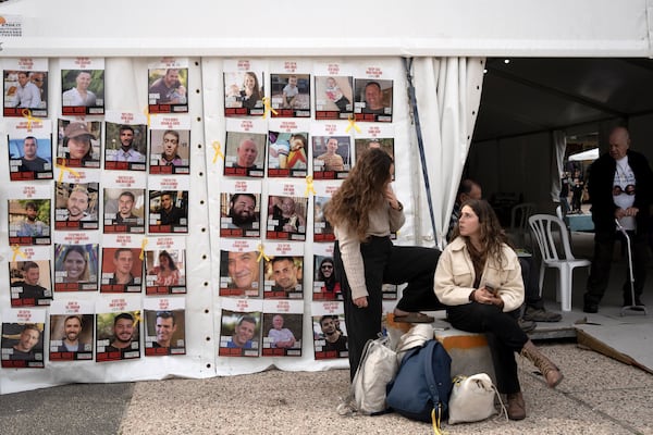 Women sit near posters of hostages held by Hamas in the Gaza Strip, in Tel Aviv, Israel, as Israel's security cabinet convened to decide whether to approve a deal that would release dozens of hostages held by militants in Gaza and pause the 15-month-war, Friday, Jan. 17, 2025. (AP Photo/Maya Alleruzzo)