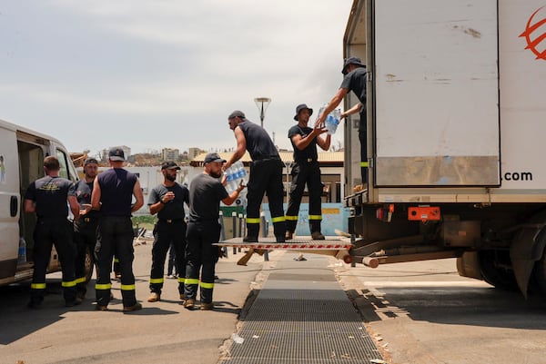 French Civil Security personnel unload water for distribution in Mamoudzou, Mayotte, Saturday, Dec. 21, 2024. (AP Photo/Adrienne Surprenant)