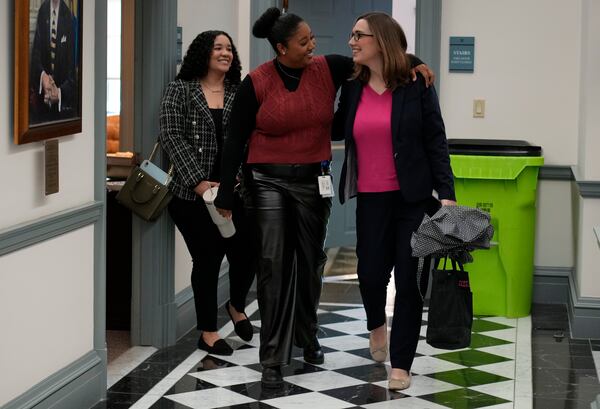 U.S.-Rep.-elect Sarah McBride, D-Del., right, is greeted by Alexis Wrease, Delaware Senate majority deputy communications director, center, and Jenna Greenlee, Delaware Senate majority digital communications specialist, left, as she arrives for her last day as a Delaware state senator at the Delaware Legislative Hall in Dover, Del., Monday, Dec. 16, 2024. (AP Photo/Carolyn Kaster)