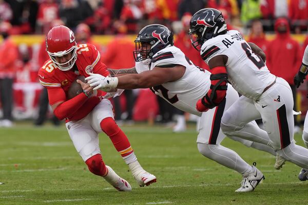 Kansas City Chiefs quarterback Patrick Mahomes, left, is tackled by Houston Texans running back Jawhar Jordan (22) and linebacker Azeez Al-Shaair (0) during the first half of an NFL football AFC divisional playoff game Saturday, Jan. 18, 2025, in Kansas City, Mo. (AP Photo/Charlie Riedel)