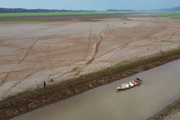 FILE - Fishermen push a boat in the Aleixo Lake amid a drought in Manaus, Amazonas state, Brazil, Sept. 24, 2024. (AP Photo/Edmar Barros, File)