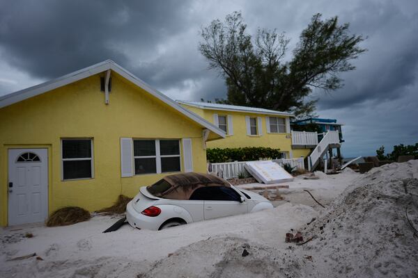 FILE - As Hurricane Milton approaches, a car sits half-buried in sand in Bradenton Beach, Fla., in the aftermath of Hurricane Helene, Oct. 8, 2024. (AP Photo/Rebecca Blackwell, File)