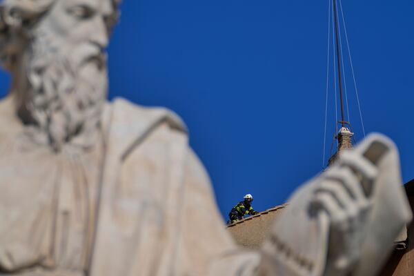 Firefighters place the chimney on the roof of the Sistine Chapel, where cardinals will gather to elect the new pope, at the Vatican, Friday, May 2, 2025. (AP Photo/Gregorio Borgia)