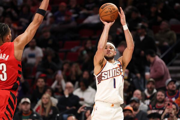 Phoenix Suns guard Devin Booker (1) prepares score to become the team's all-time leading scorer as Portland Trail Blazers forward Toumani Camara (33) defends during the second half of an NBA basketball game Monday, Feb. 3, 2025, in Portland, Ore. (AP Photo/Amanda Loman)