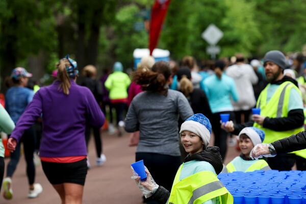 Eddie Ashton, 10, of St. Paul, Minn., hands out a reusable silicone cup by Hiccup along the PNC Women Run the Cities route on Saturday, May 17, 2025, in Minneapolis. (AP Photo/Ellen Schmidt)