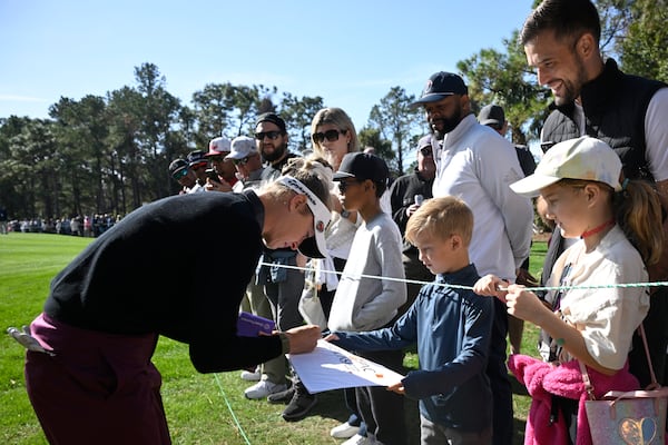 Nelly Korda, left, signs an autograph after leaving the third green during the first round of the PNC Championship golf tournament, Saturday, Dec. 21, 2024 in Orlando. (AP Photo/Phelan M. Ebenhack)