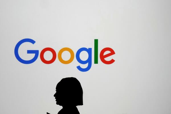 A woman walks by a giant screen with a logo at an event at the Paris Google Lab on the sidelines of the AI Action Summit in Paris, Sunday, Feb. 9, 2025. (AP Photo/Thibault Camus)