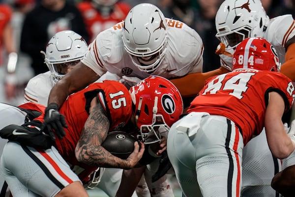 Georgia quarterback Carson Beck (15) runs into Texas defensive lineman Vernon Broughton (45) during the first half of the Southeastern Conference championship NCAA college football game, Saturday, Dec. 7, 2024, in Atlanta. (AP Photo/Mike Stewart)