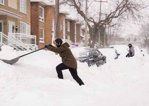 People shovel snow to dig out their cars in Montreal, Monday, Feb. 17, 2025, after over 70 centimetres of snow fell in 4 days, breaking a snowfall record in the city. (Christinne Muschi/The Canadian Press via AP)