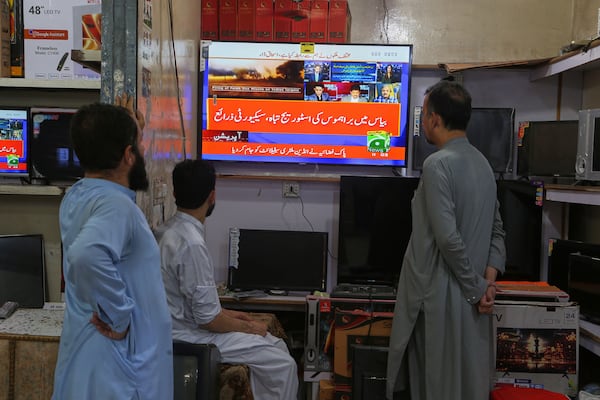 Shopkeepers watch a news channel telecasting ongoing military tension between Pakistan and India, at a shop in Peshawar, Pakistan, Saturday, May 10, 2025. (AP Photo/Muhammad Sajjad)
