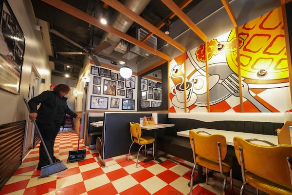 An egg on a mural displaying breakfast items as Teaira Booker sweeps, at The Breakfast Brothers restaurant, Wednesday, Feb. 12, 2025, in Arlington, Texas. (AP Photo/Julio Cortez)