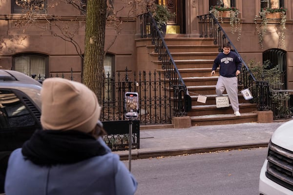 A resident steps over a chain restricting access to the brownstone where Carrie Bradshaw lived in “Sex and the City”, in New York, Wednesday, Jan. 15, 2025. The city’s Landmarks Preservation Commission approved an application for a metal gate for the front staircase of the Manhattan brownstone to keep away tourists who endlessly trespass and pose for pictures. (AP Photo/Yuki Iwamura)