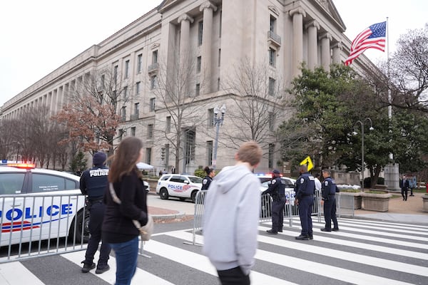 Pedestrians walk as police secure the area around the Justice Department before President Donald Trump speaks Friday, March 14, 2025, in Washington. (AP Photo/Jacquelyn Martin)