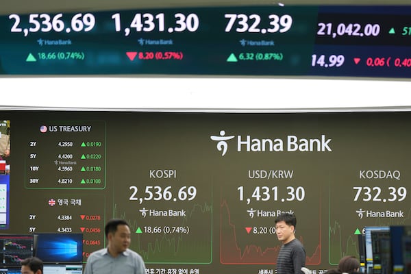 Currency traders walk near the screens showing the Korea Composite Stock Price Index (KOSPI), left, and the foreign exchange rate between U.S. dollar and South Korean won at a foreign exchange dealing room in Seoul, South Korea, Wednesday, Jan. 22, 2025. (AP Photo/Lee Jin-man)