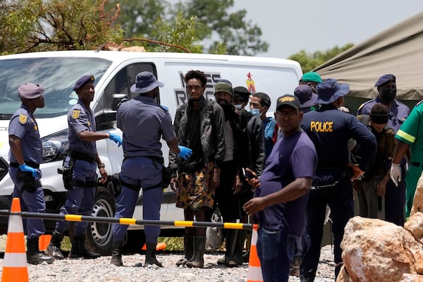 Miners are escorted by police officers after being rescued from below ground in an abandoned gold mine for months, in Stilfontein, South Africa, Tuesday, Jan. 14, 2025. (AP Photo/Themba Hadebe)