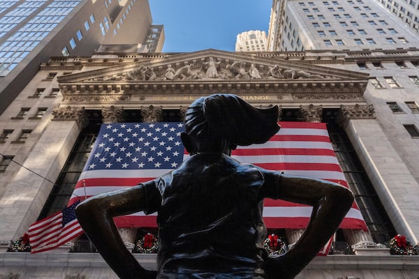 The New York Stock Exchange is shown behind the statue titled "Fearless Girl", Thursday, Dec. 12, 2024, in New York. (AP Photo/Julia Demaree Nikhinson)