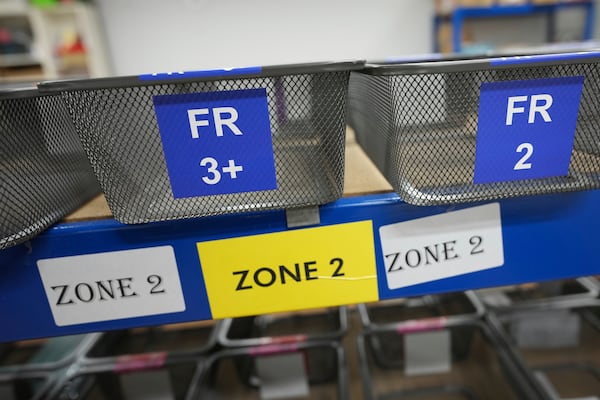 Baskets showing country codes and label designations await packet of school children's labels at 'My Nametags' factory in London, Thursday, Jan. 30, 2025. (AP Photo/Alastair Grant)