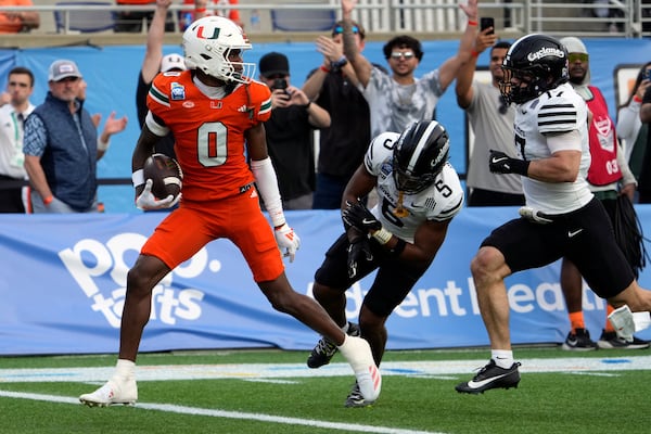 Miami wide receiver Joshisa Trader (0) scores a touchdown on a pass play as he gets past Iowa State defensive back Myles Purchase (5) and defensive back Beau Freyler, right, during the first half of the Pop Tarts Bowl NCAA college football game, Saturday, Dec. 28, 2024, in Orlando, Fla. (AP Photo/John Raoux)