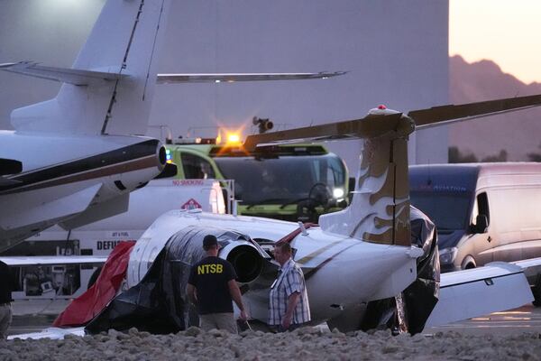 Investigators look at a crashed Learjet at Scottsdale Airport after it collided with a parked plane Monday, Feb. 10, 2025, in Scottsdale, Ariz. (AP Photo/Ross D. Franklin)