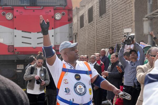 Egyptian wrestler Ashraf Mahrous, better known as Kabonga, greets his fans after he pulled a train for nearly 10 meters, 33 feets, at Ramses Station in Cairo, Egypt, Thursday, March 13, 2025. (AP Photo/Amr Nabil)