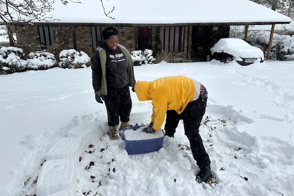 Tyshae Sanders and Terrell Bryant work on building an igloo using a plastic bucket in Little Rock, Ark., Friday, Jan. 10, 2025. (AP Photo/Andrew DeMillo)