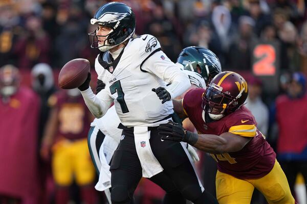 Philadelphia Eagles quarterback Kenny Pickett (7) avoids a tackle by Washington Commanders linebacker Bobby Wagner (54) during the second half of an NFL football game, Sunday, Dec. 22, 2024, in Landover, Md. (AP Photo/Stephanie Scarbrough)