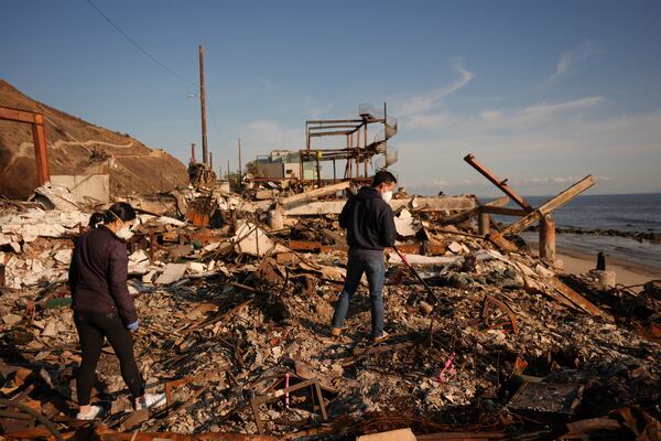 Tony Lai, center, rakes through the remains of his fire-ravaged beachfront property with his wife Everlyn in the aftermath of the Palisades Fire Tuesday, Jan. 28, 2025 in Malibu, Calif. (AP Photo/Jae C. Hong)