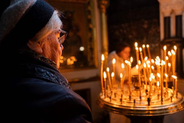 The parishioner prays next to prayer candles in St. Volodymyr's Cathedral in Kyiv, Ukraine, Sunday, Feb. 23, 2025. (AP Photo/Alex Babenko)