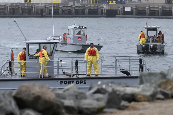 U.S. Navy boats work along the shore near Shelter Island after a U.S. Navy plane crashed into the San Diego Bay, Wednesday, Feb. 12, 2025, in San Diego. (AP Photo/Denis Poroy)