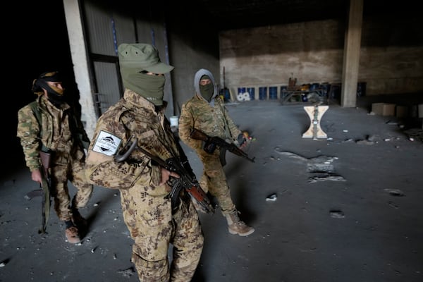 Syrian members of the rebel group walk at a warehouse where the amphetamine pills known as Captagon was manufactured before the fall of Bashar Assad government in Douma city, outskirts of Damascus, Syria, Friday, Dec. 13, 2024. (AP Photo/Hussein Malla)