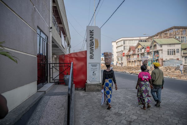 People walk past a closed bank in downtown Goma, Democratic Republic of Congo, Thursday, Feb. 27, 2025, one month after Rwanda-backed M23 rebels took the city. (AP Photo/Moses Sawasawa)