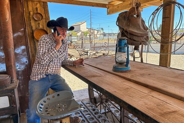Rancher Brantley Baird takes a phone call while sitting in the shade at his pioneer museum in Joseph City, Ariz., Wednesday, April 23, 2025. (AP Photo/Susan Montoya Bryan)