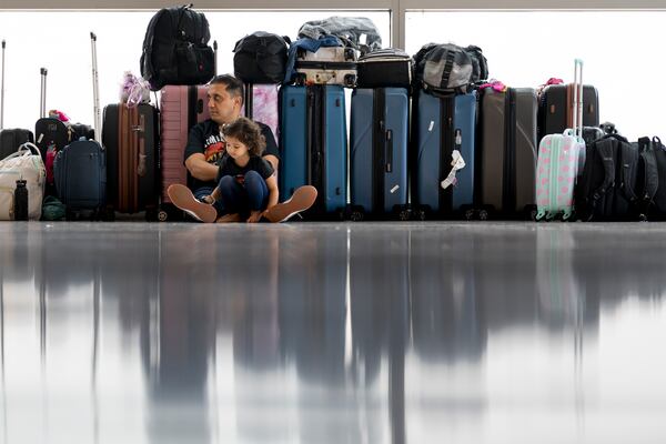 FILE - Samuel Tadros and his daughter Serenity 3, sit with the family's bags after their flight to New York was cancelled at the Nashville international Airport Thursday, May 23, 2024, in Nashville, Tenn., ahead of Memorial Day. (AP Photo/George Walker IV, File)