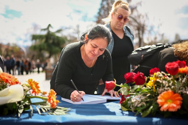 A woman writes a condolence message for the victims of a massive nightclub fire in the town of Kocani, North Macedonia, Monday, March 17, 2025, (AP Photo/Armin Durgut)