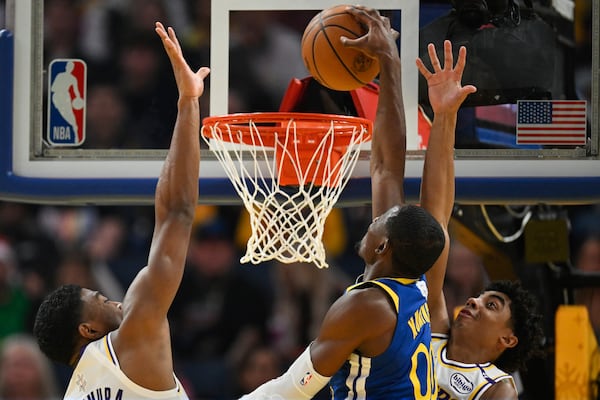 Golden State Warriors forward Jonathan Kuminga (00) dunks against Los Angeles Lakers forward Rui Hachimura, left, and guard Max Christie, right, during the first half of an NBA basketball game Wednesday, Dec. 25, 2024, in San Francisco. (AP Photo/Eakin Howard)